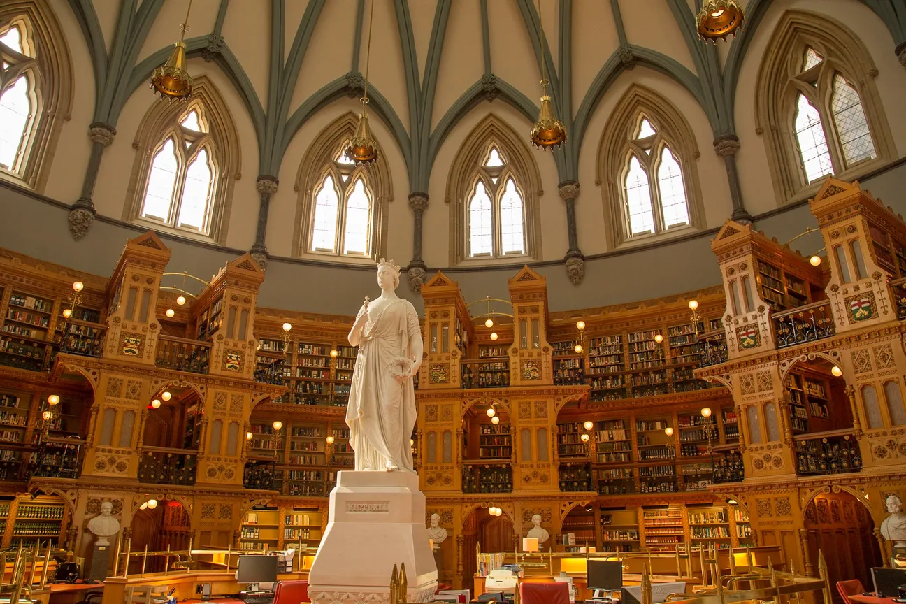 Interior of the Library of Parliament showing the ornate Gothic Revival reading room and the statue of Queen Victoria