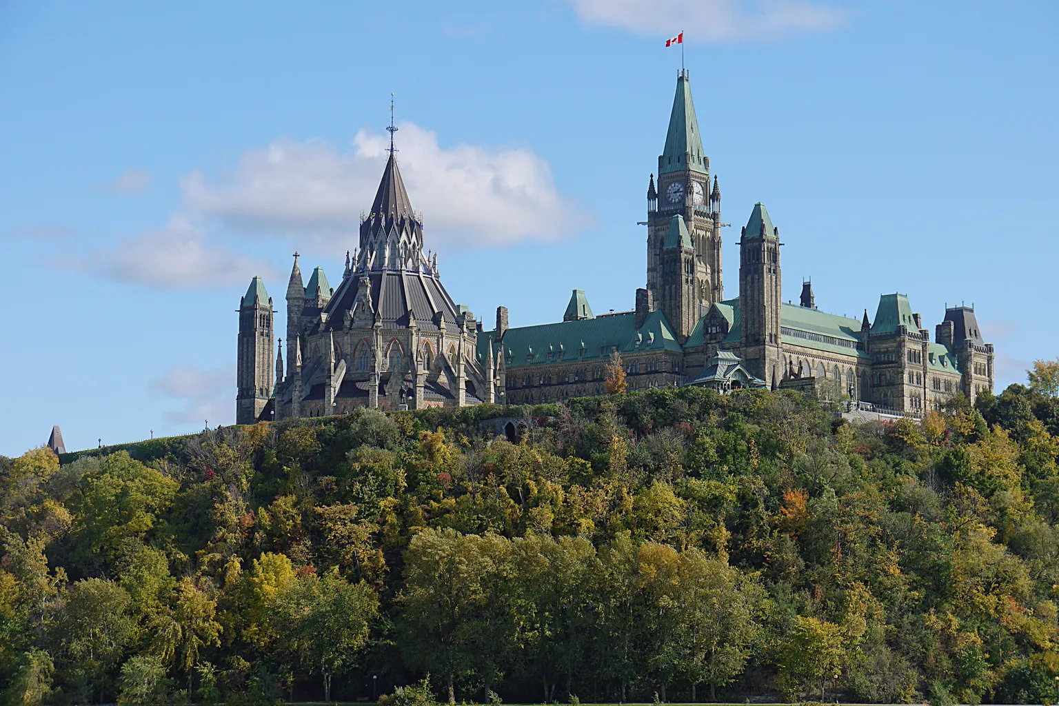 Parliament Hill from the Ottawa River — copper roofs of the East and West blocks above the limestone cliff