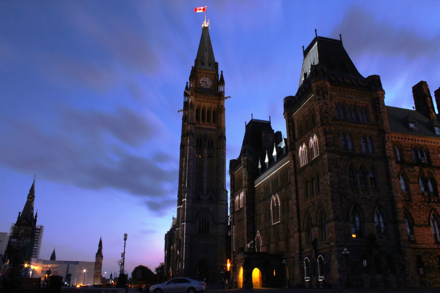 Centre Block and the Peace Tower on Parliament Hill at dusk, lit against a blue evening sky